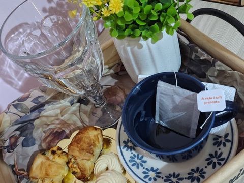 Bandeja de boas-vindas com chá, água, flores amarelas e petiscos